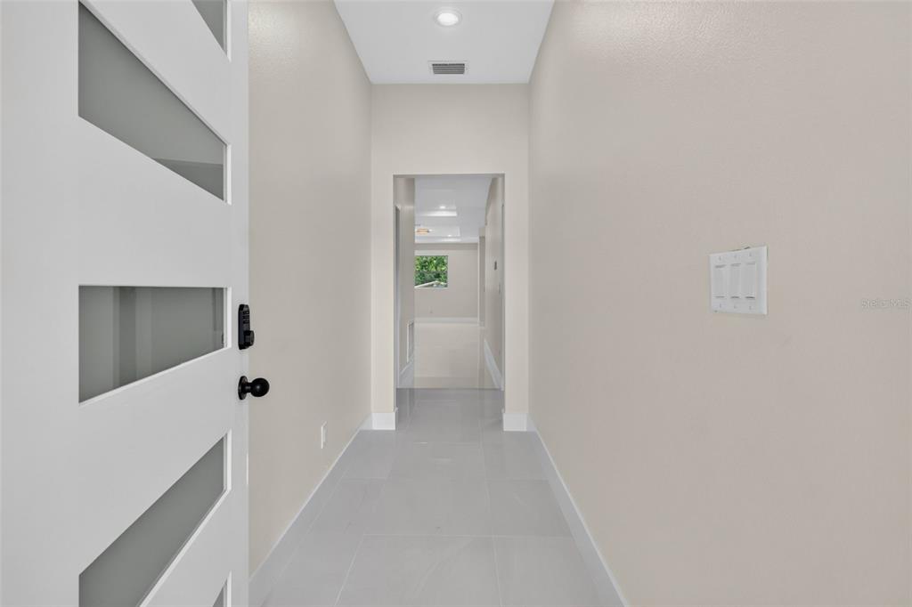 A bright entryway features light-colored tile flooring, neutral walls, and a modern white front door — 619 W VALENCIA STREET, LAKELAND, FL
