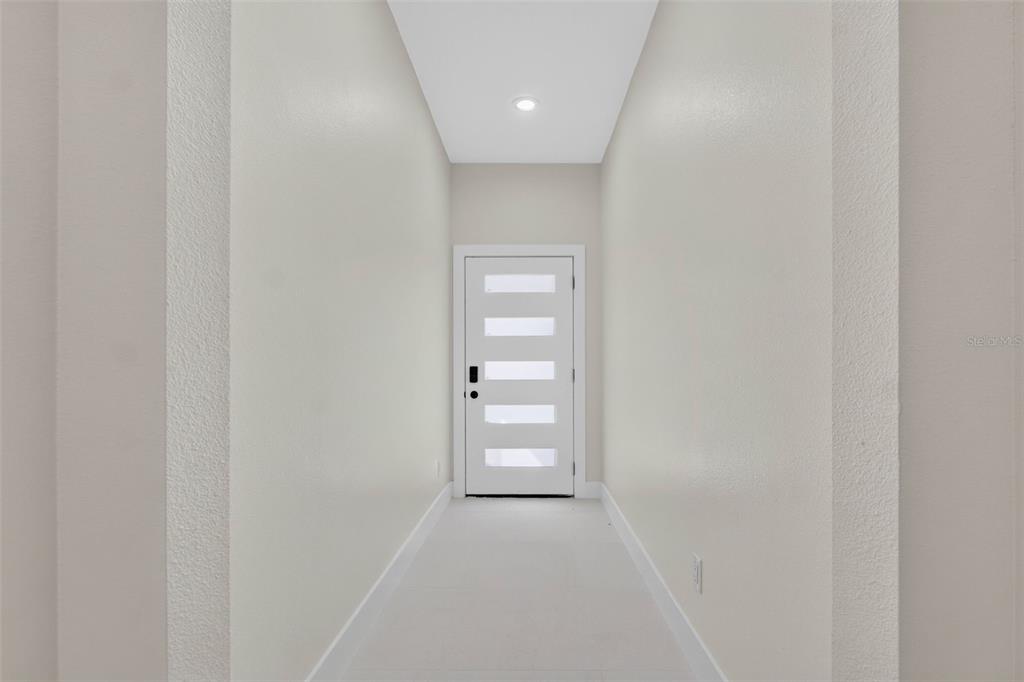 A bright, narrow entryway features white walls, light tile flooring, and a modern front door — 619 W VALENCIA STREET, LAKELAND, FL