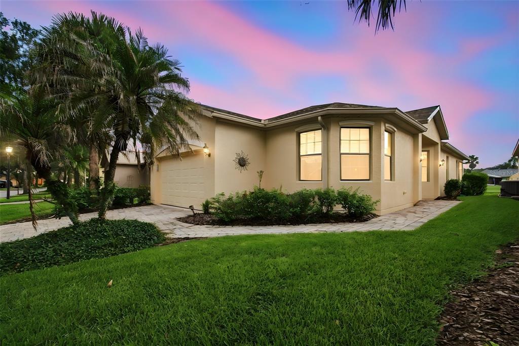 A single-story house with a beige stucco exterior, a two-car garage, and a paved walkway — 133 GRAND CANAL DRIVE, POINCIANA, FL