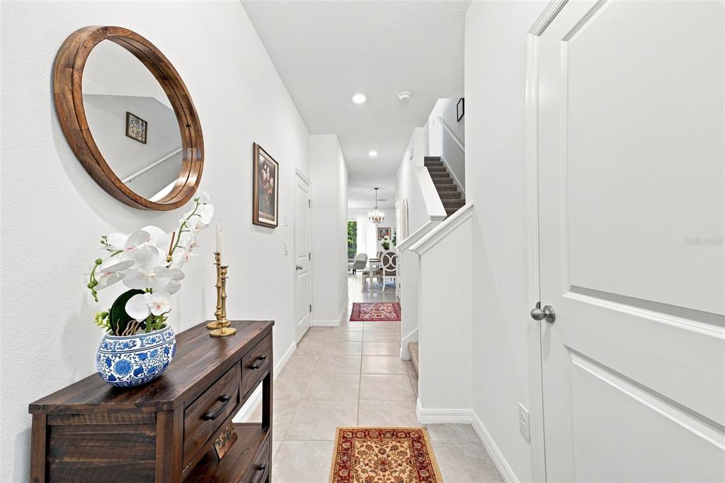 A bright entryway features a wooden console table, a round mirror, and a staircase — 32898 PEZ LANDING LANE, WESLEY CHAPEL, FL