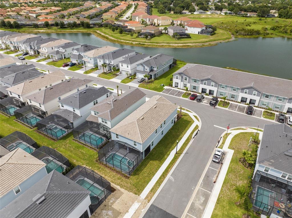 An aerial view shows suburban houses with screened-in pools and a nearby lake — 7180 OAKMOSS LOOP, DAVENPORT, FL