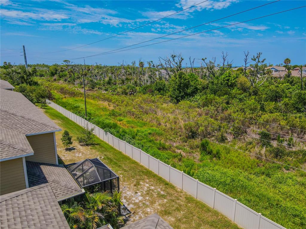 An aerial view shows a house with a screened patio, a fence, and surrounding vegetation — 3029 JACOB CROSSING LANE, HOLIDAY, FL