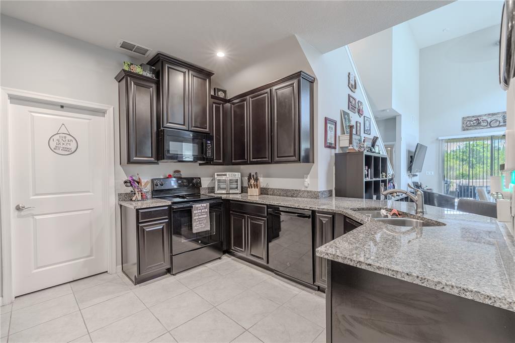 A kitchen features dark wood cabinets, granite countertops, and stainless steel appliances — 3029 JACOB CROSSING LANE, HOLIDAY, FL