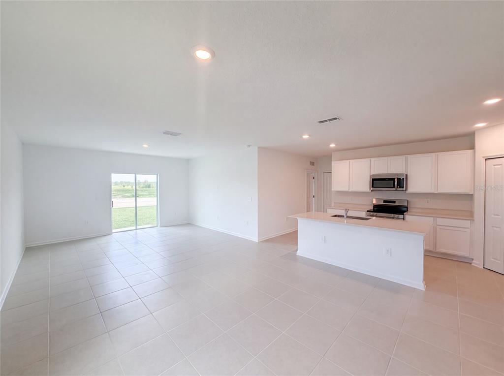 An open-concept kitchen and living area features white cabinetry, a central island, and tile flooring — 4373 RIVER BEACON BOULEVARD, DAVENPORT, FL