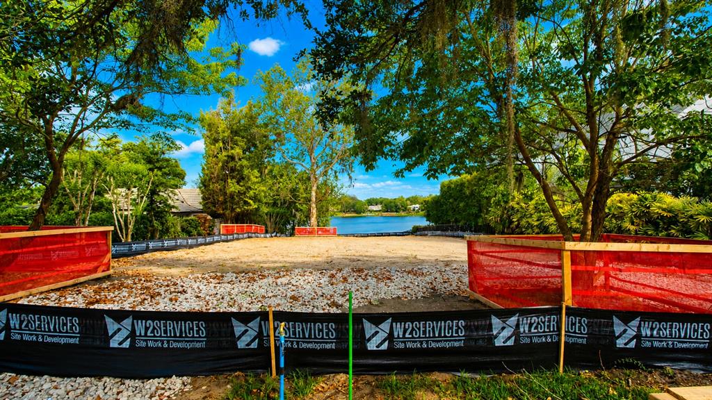 A cleared, fenced construction lot with gravel ground overlooks a lake surrounded by trees — 313L SYLVAN DRIVE, WINTER PARK, FL