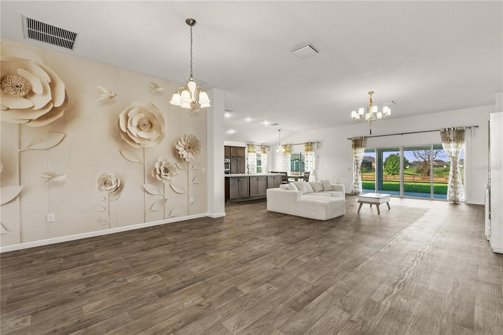A hallway with wood-look flooring leads to a living area featuring a console table — 11216 ROZ WAY, OXFORD, FL