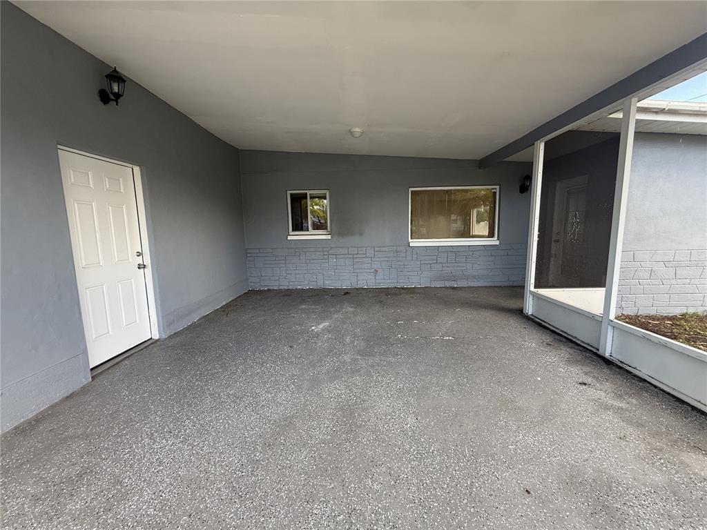 A gray-painted carport features a white door, two windows, and a screened-in porch area — 5171 98TH AVENUE N, PINELLAS PARK, FL