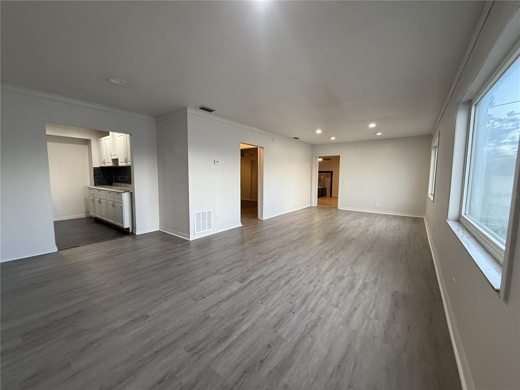 An interior view of a living room with gray wood-look flooring and white walls — 5171 98TH AVENUE N, PINELLAS PARK, FL