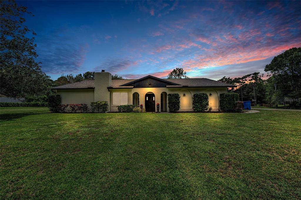 A single-story house with a light-colored exterior and a dark roof at twilight — 7812 WINDWARD WAY, ODESSA, FL