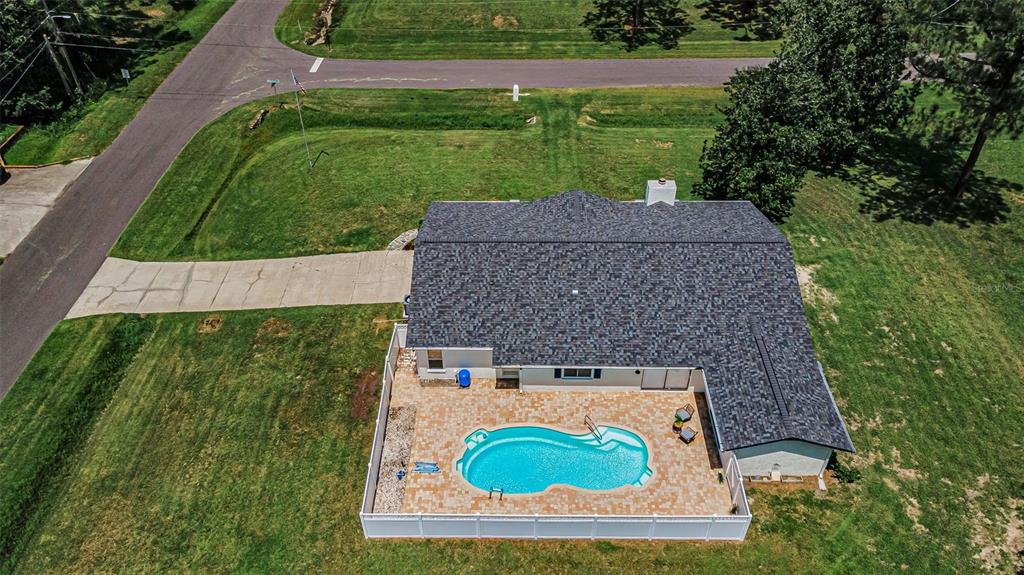 An aerial view shows a house with a shingled roof, a fenced pool, and driveway — 7812 WINDWARD WAY, ODESSA, FL