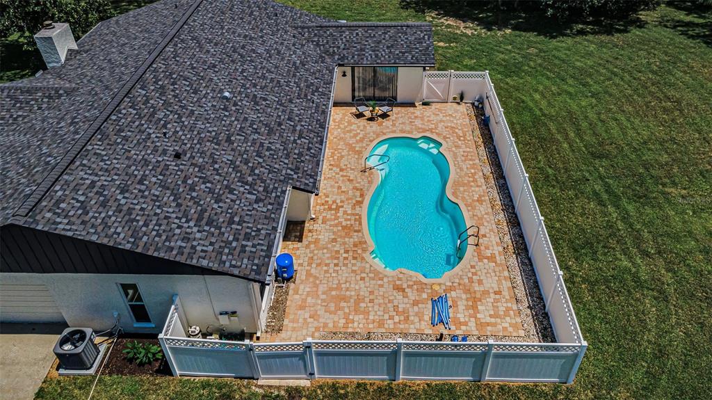 An aerial view shows a house with a shingled roof, a paved patio, and a pool — 7812 WINDWARD WAY, ODESSA, FL