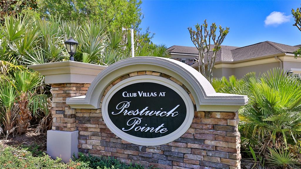 A stone monument sign for Club Villas at Prestwick Pointe stands amidst lush landscaping — 822 ALDENHAM LANE, ORMOND BEACH, FL