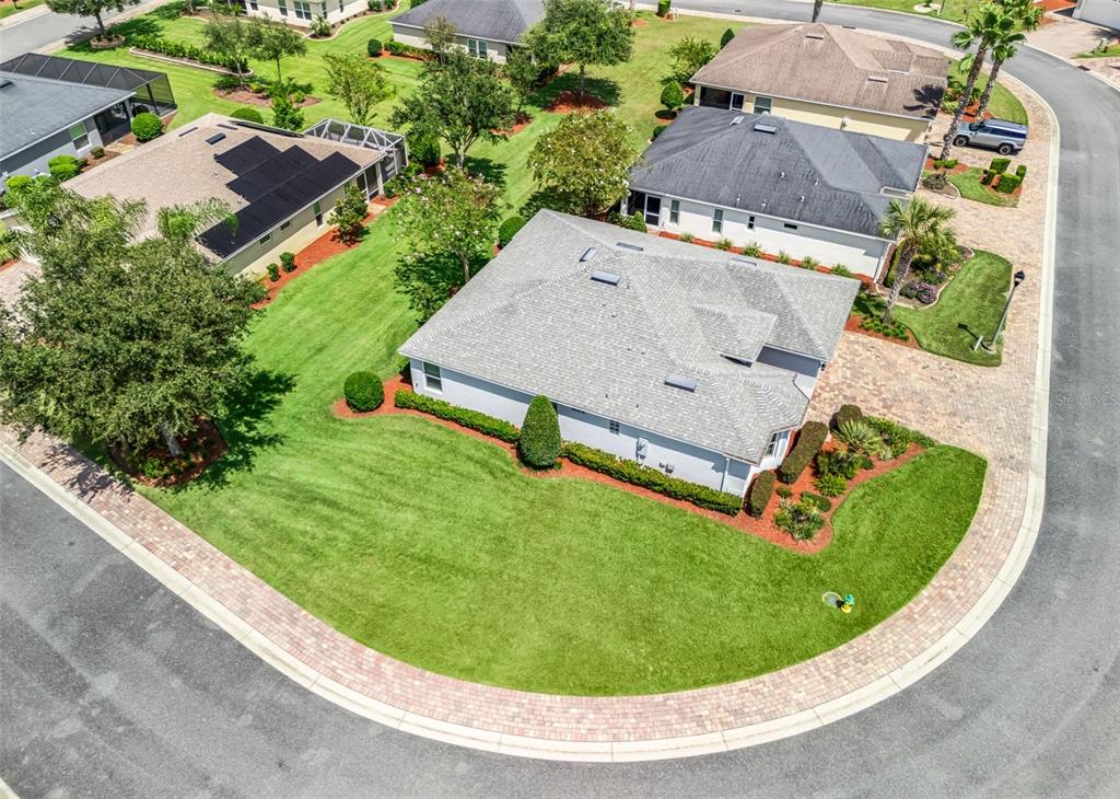 An aerial view shows a suburban house with a gray roof on a corner lot — 10038 KETCH KAY LANE, OXFORD, FL