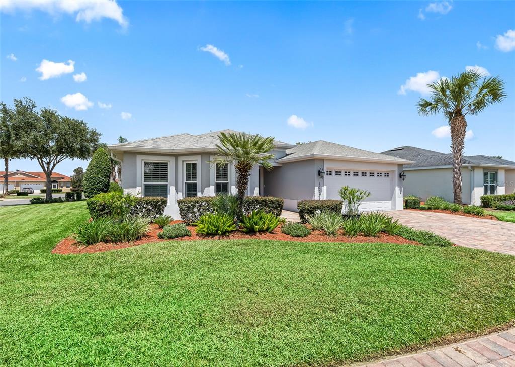 A single-story house with a gray exterior, a two-car garage, and a landscaped front yard — 10038 KETCH KAY LANE, OXFORD, FL