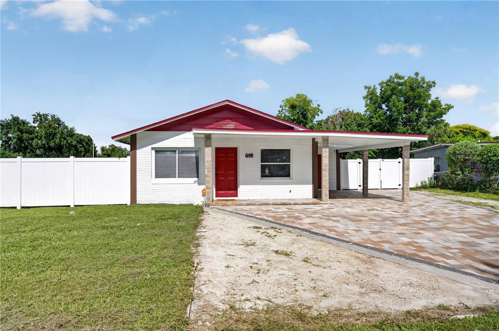 A single-story white brick house with a red roof, red front door, and attached carport — 1241 DEEROCK DRIVE, ORLANDO, FL