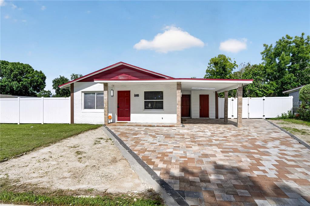 A single-story house with a white brick exterior, red doors, and a paved driveway — 1241 DEEROCK DRIVE, ORLANDO, FL