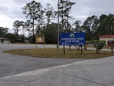 A blue sign for Whispering Pines Club House stands in a paved parking lot — 224 PLUMOSA DRIVE, GEORGETOWN, FL