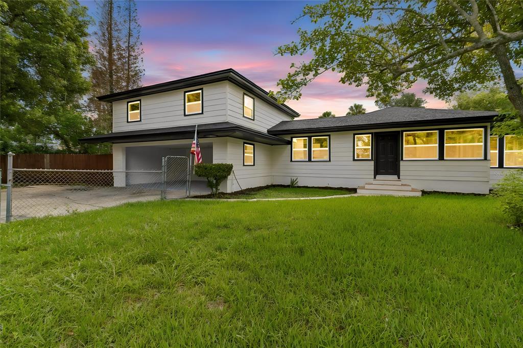 A white, single-story house with a dark roof sits on a grassy lot — 400 PLUMOSA DRIVE, SANFORD, FL