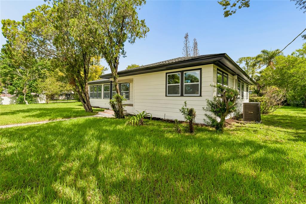 A single-story white house with a black roof and trim sits behind a chain-link fence — 400 PLUMOSA DRIVE, SANFORD, FL