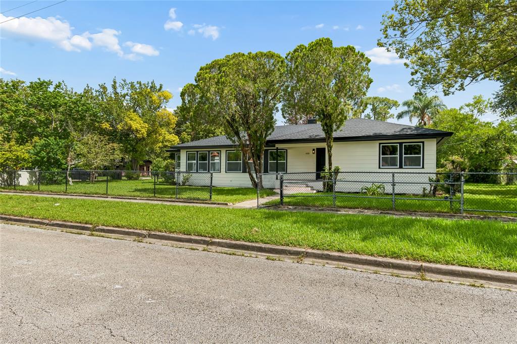 A single-story house with white siding, dark trim, and a dark roof sits on grass — 400 PLUMOSA DRIVE, SANFORD, FL