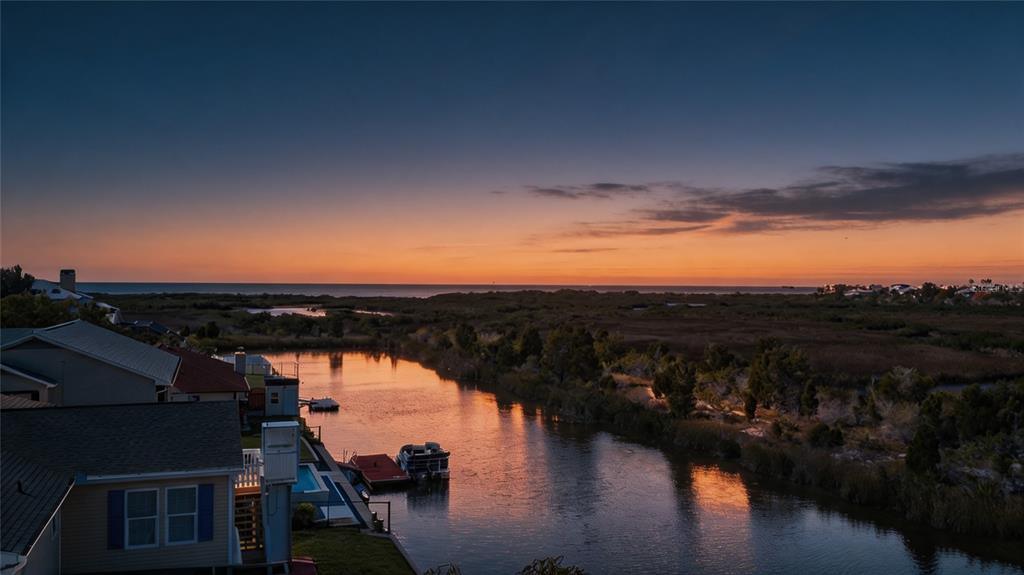 An elevated view of a canal at sunset with houses, a boat, and coastal vegetation — 3460 CRAPE MYRTLE DRIVE, HERNANDO BEACH, FL