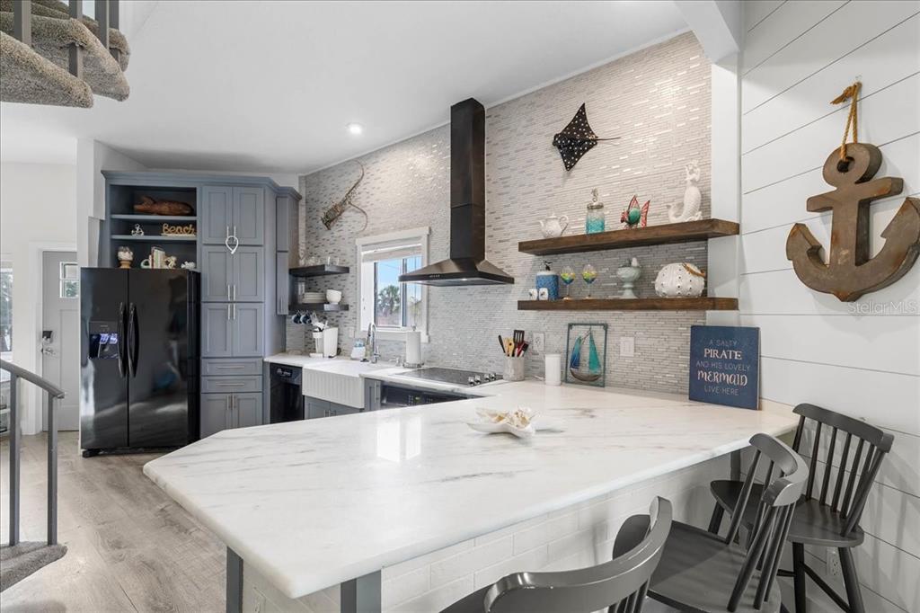 A kitchen features a white marble island, grey cabinetry, open shelving, and a tiled backsplash — 3460 CRAPE MYRTLE DRIVE, HERNANDO BEACH, FL