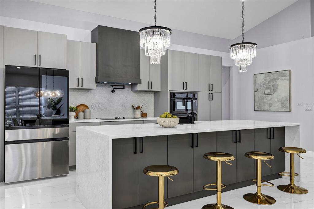 A modern kitchen features gray cabinetry, a white waterfall island, and two crystal pendant lights — 13712 DEVLIN COURT, ORLANDO, FL