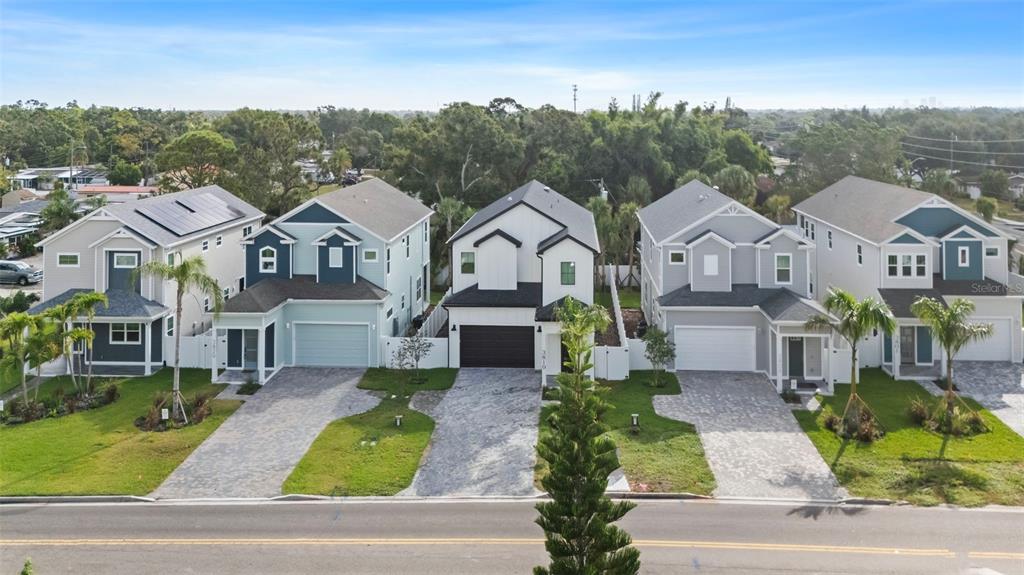 An aerial view shows a row of four modern two-story suburban houses with paved driveways — 3839 71ST STREET N, ST PETERSBURG, FL