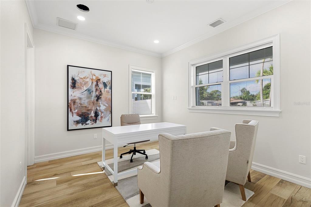 A home office features a white desk, two beige armchairs, abstract wall art, and flooring — 3839 71ST STREET N, ST PETERSBURG, FL
