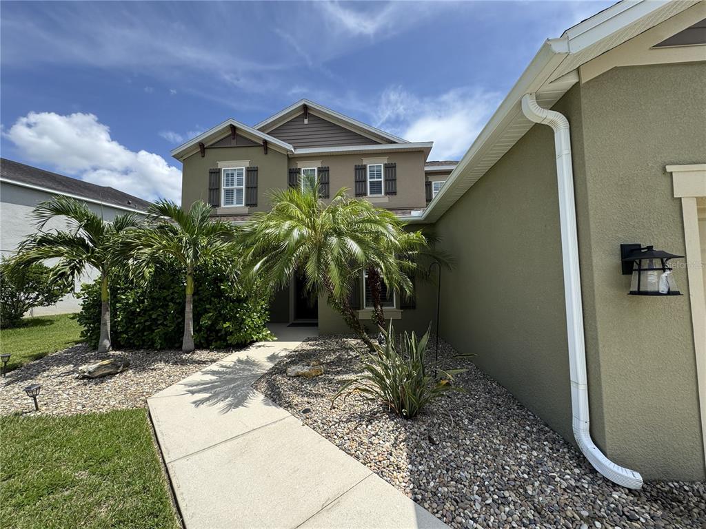 A two-story house with a tan stucco exterior, palm trees, and a concrete walkway — 5847 PALMER RANCH PARKWAY, SARASOTA, FL