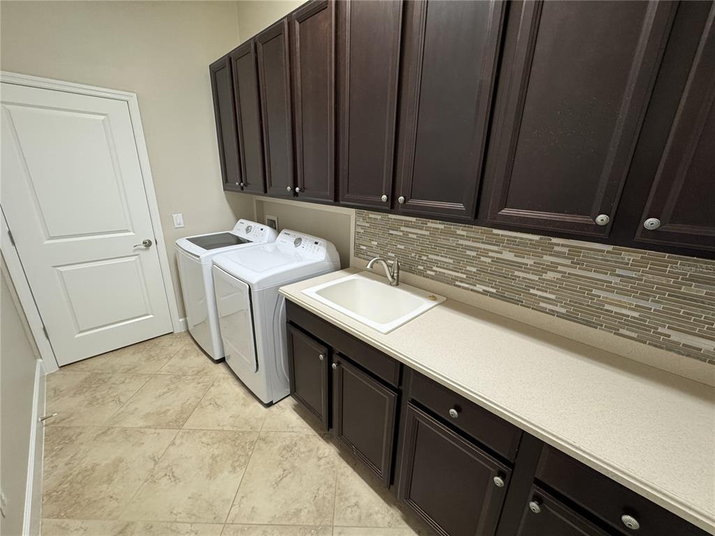 A laundry room features dark wood cabinets, a white utility sink, and white appliances — 5847 PALMER RANCH PARKWAY, SARASOTA, FL
