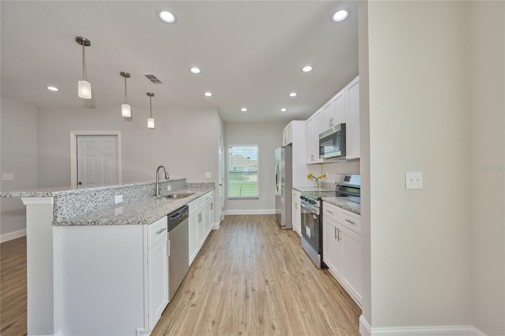 An open-concept living area features wood-look flooring, a fireplace, and a kitchen with white cabinets — 2581 POINCIANA DRIVE, INDIAN LAKE ESTATES, FL