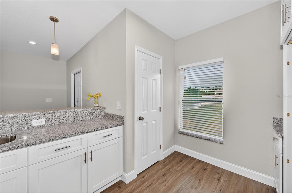 A kitchen with white cabinets, granite countertops, and a breakfast bar overlooking a dining area — 2581 POINCIANA DRIVE, INDIAN LAKE ESTATES, FL