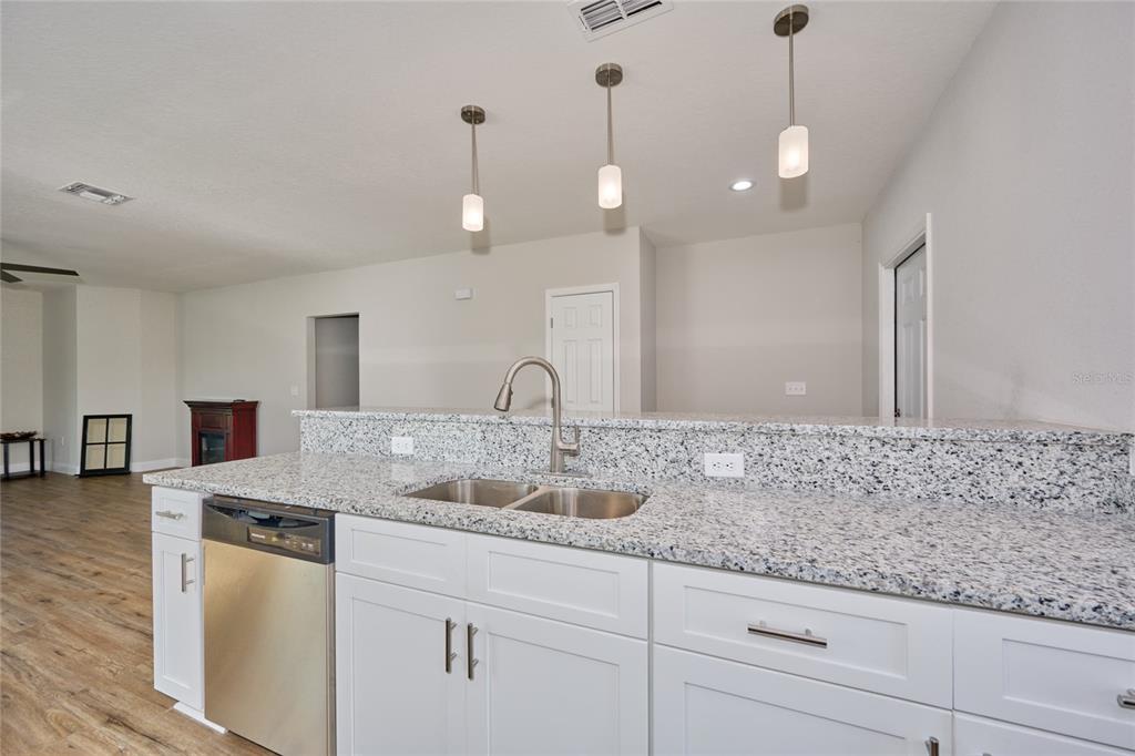 A kitchen with white cabinets, granite countertops, and wood-look flooring — 2581 POINCIANA DRIVE, INDIAN LAKE ESTATES, FL
