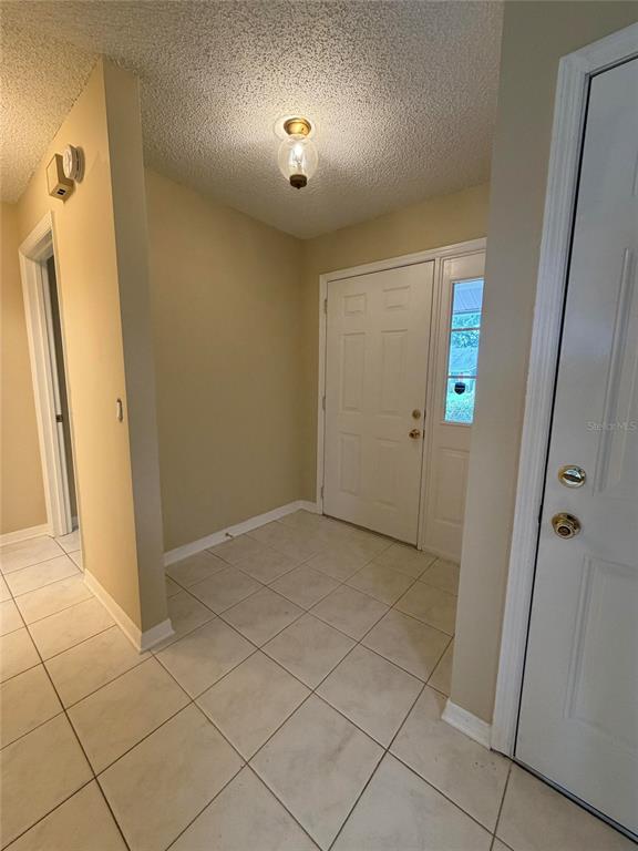 An entryway features beige tile flooring, a textured ceiling, and a white front door — 5108 LAZY OAKS DRIVE UNIT 5108, WINTER PARK, FL