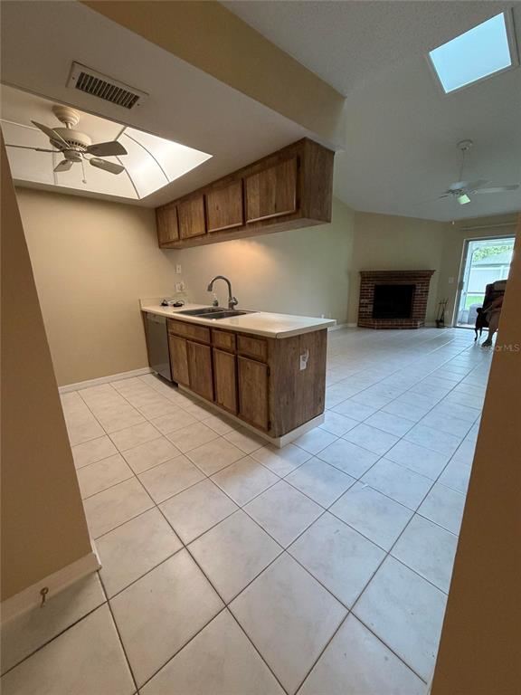 A kitchen with wood cabinets and tile flooring opens into a living area with a fireplace — 5108 LAZY OAKS DRIVE UNIT 5108, WINTER PARK, FL