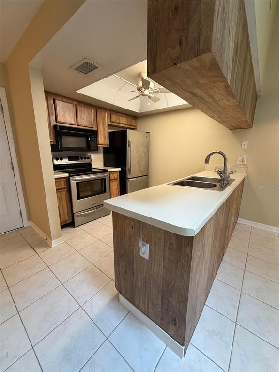 A kitchen features wood-look cabinetry, a stainless steel stove, and a white countertop breakfast bar — 5108 LAZY OAKS DRIVE UNIT 5108, WINTER PARK, FL