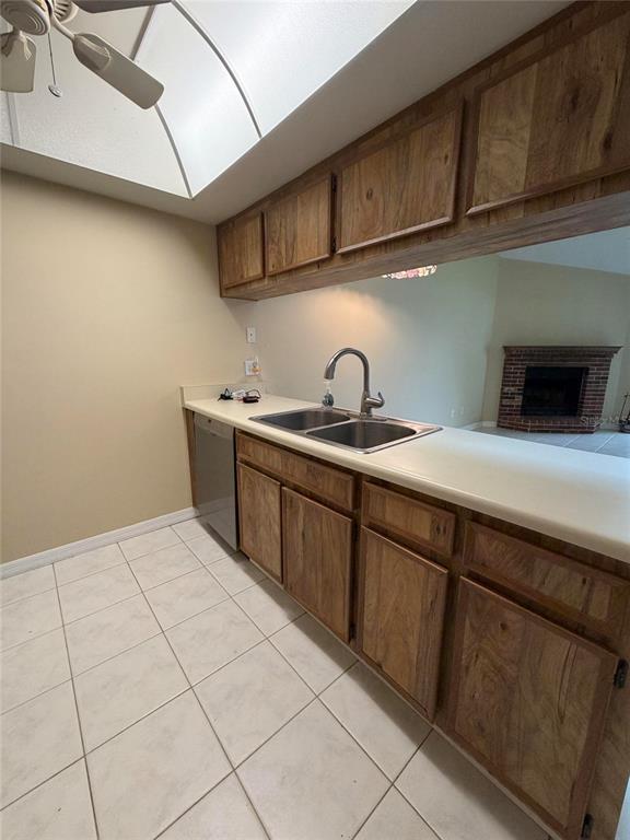 A kitchen features wooden cabinets, a double-basin sink, and white tile flooring — 5108 LAZY OAKS DRIVE UNIT 5108, WINTER PARK, FL