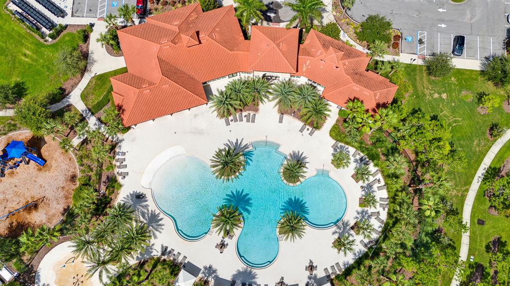 An aerial view shows a community swimming pool with palm trees and an adjacent building — 6435 DEVESTA LOOP, PALMETTO, FL