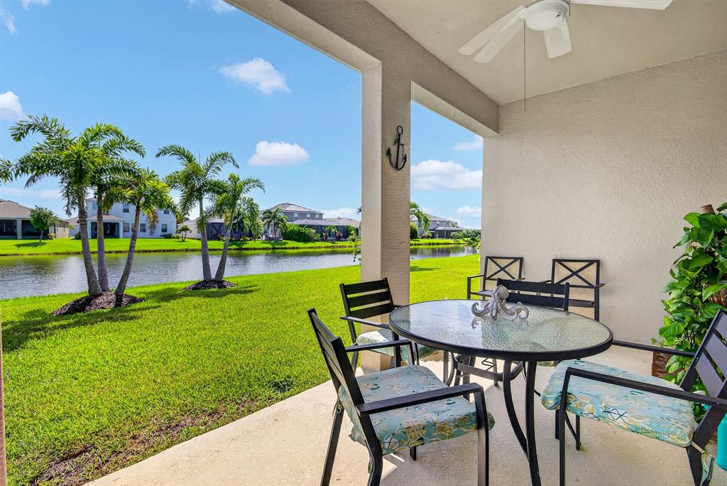 A covered patio features a glass-topped table, chairs, and a view of a pond — 6435 DEVESTA LOOP, PALMETTO, FL