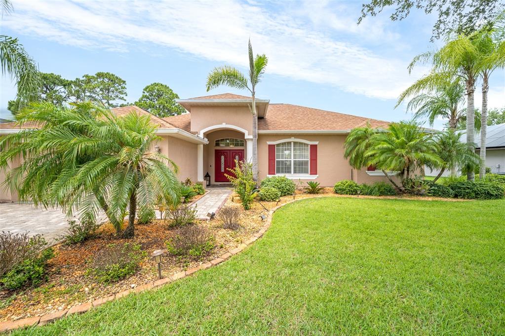 A single-story house with a red front door, palm trees, and a landscaped front yard — 241 DEVLIN COURT, PALM BAY, FL