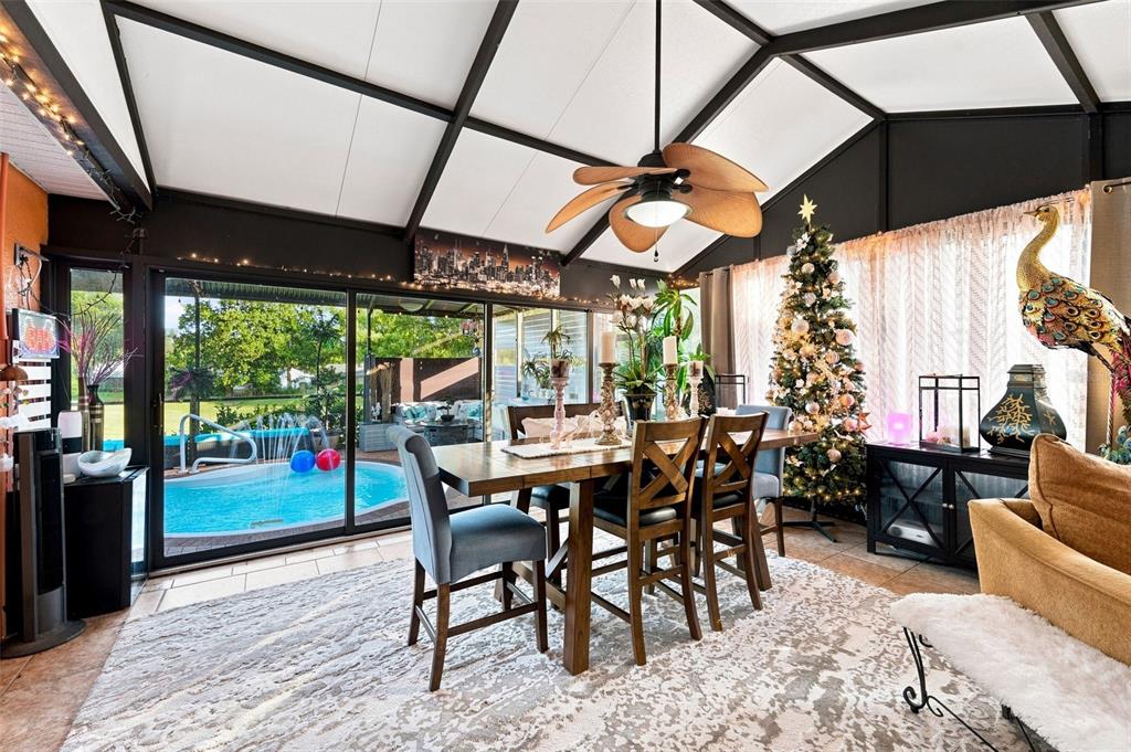 A sunroom features a dining set, a Christmas tree, and sliding doors overlooking a pool — 8136 GOLF CLUB COURT, HUDSON, FL