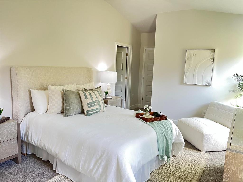 A bedroom features a bed with a textured headboard, a white chair, and neutral decor — 3635 LINDBERGH STREET, LAKELAND, FL