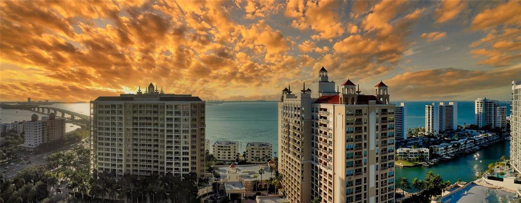 An aerial view of high-rise apartment buildings overlooking a bay at sunset — 35 WATERGATE DRIVE UNIT 806, SARASOTA, FL