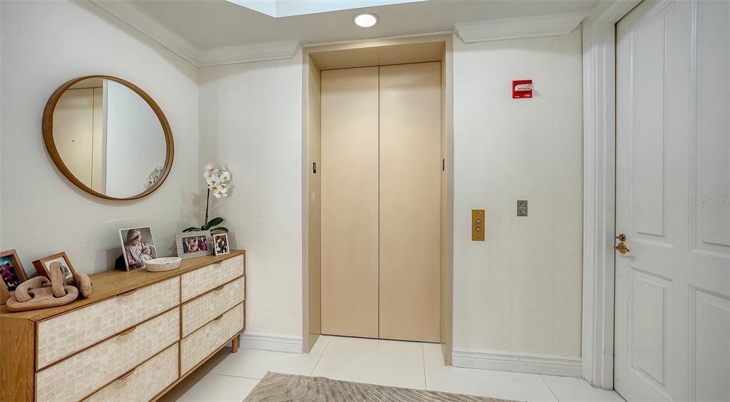 A hallway features a light-colored dresser, a round mirror, and a closed elevator door — 35 WATERGATE DRIVE UNIT 806, SARASOTA, FL