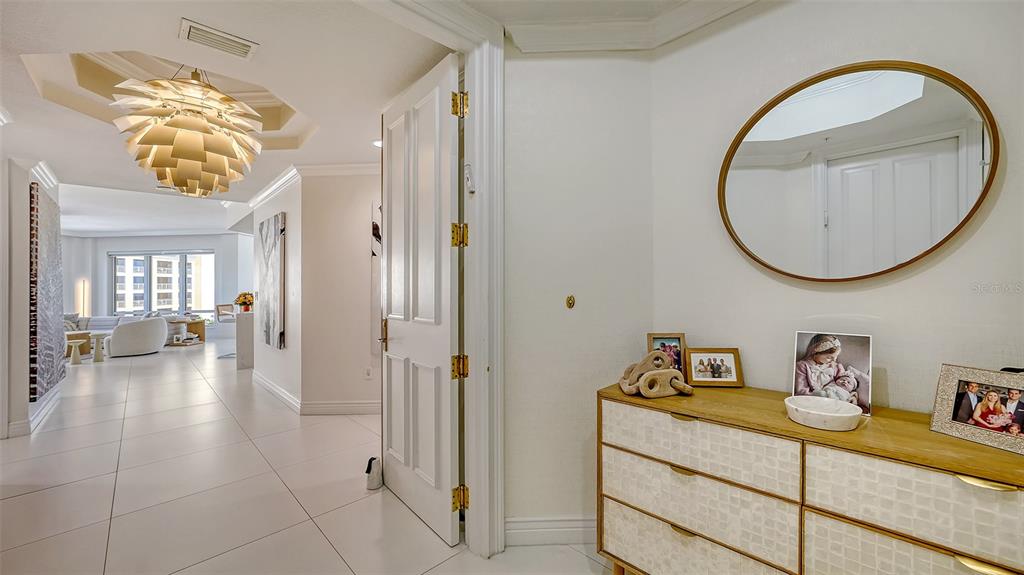 A bright entryway features white tile floors, a modern chandelier, and a wooden chest — 35 WATERGATE DRIVE UNIT 806, SARASOTA, FL