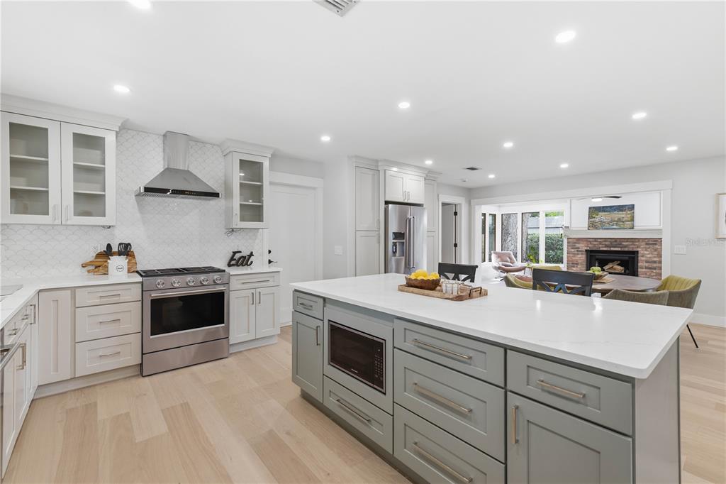 A modern kitchen features light gray cabinetry, a large central island, and stainless steel appliances — 2218 HENNESEN DRIVE, CLEARWATER, FL