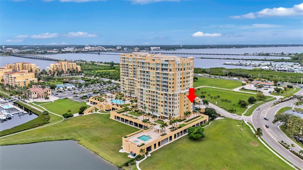 An aerial view shows a tall, tan residential building with a pool and surrounding grounds — 140 RIVIERA DUNES WAY UNIT 306, PALMETTO, FL