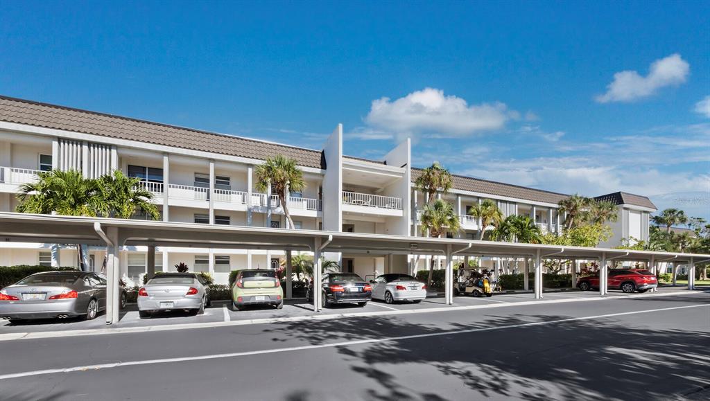 A multi-story apartment building with a covered parking area in the foreground — 4350 CHATHAM DRIVE UNIT 105, LONGBOAT KEY, FL