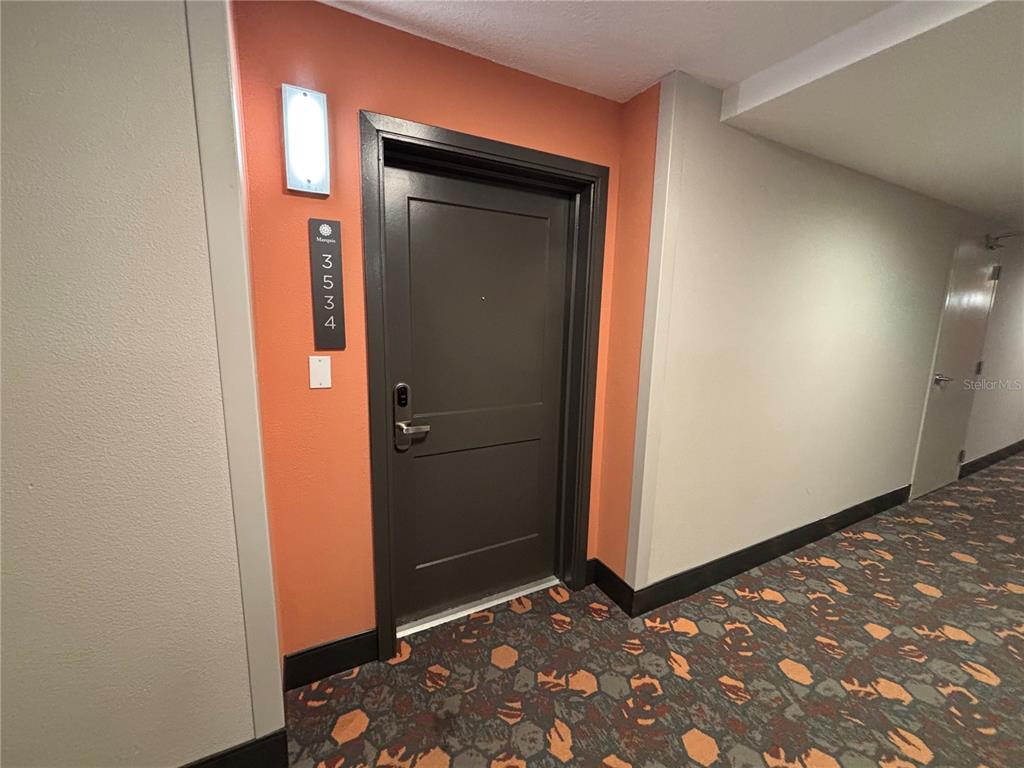 A dark door with the number 3534 is set against an orange wall in a hallway — 14501 GROVE RESORT AVENUE UNIT 3534, WINTER GARDEN, FL